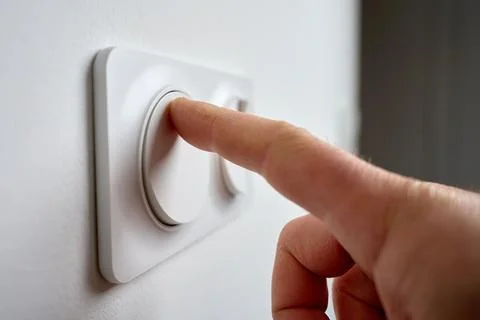 Hand pressing light switch to turn on lighting Stock Photos