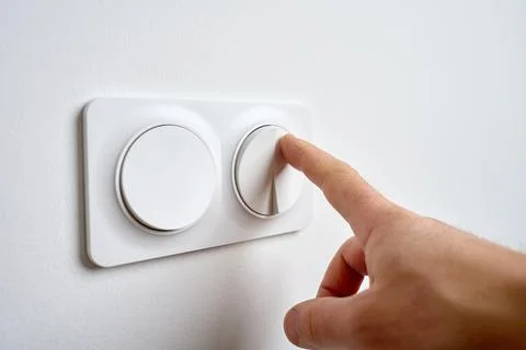 Hand pressing light switch to turn on lighting Stock Photos