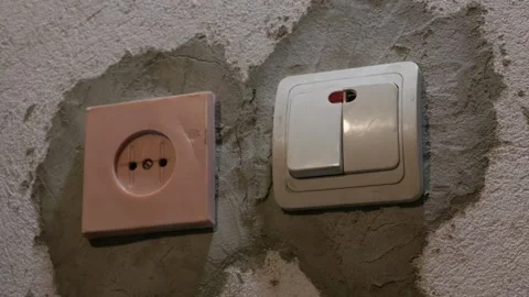 Hand Pressing Light Switch on Unfinished Plaster Wall During Home Renovation Stock Footage 335642411