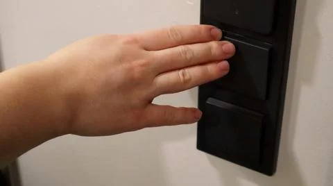 A hand is pressing a light switch on a wall. Foto stock