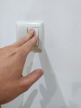 Hand pressing light switch on white wall. Symbolizes control, power, action,  Stock Photos