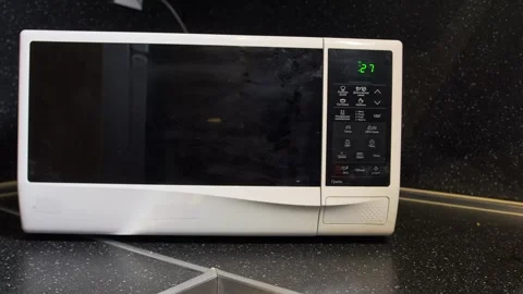 Hand pressing microwave buttons close-up view, selecting cooking program on 動画素材 333649289