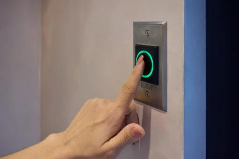 Hand Pressing a Modern Elevator Button That Features a Green Light Indicator for Foto stock
