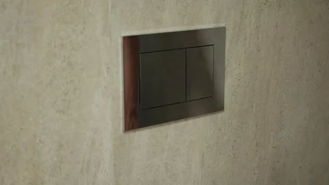 Hand pressing modern flush button on a sleek toilet wall, showcasing Video stock 313726079