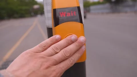 Hand pressing pedestrian crossing wait button at intersection 動画素材 338162239