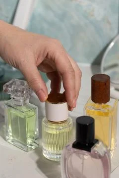 Hand pressing perfume bottle cap on vanity display of luxury fragrance bottle 스톡 사진