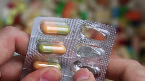 Hand pressing pills out of blister package Stock Footage 24480894