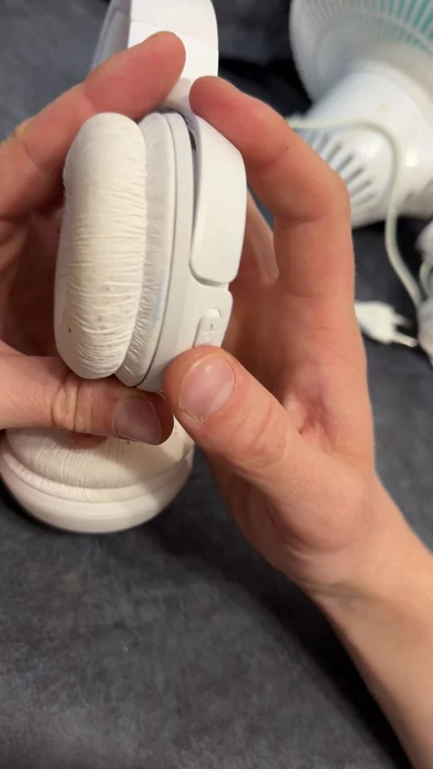 Hand pressing power button on wireless headphones close up, turning on portable Stock Footage 337121290