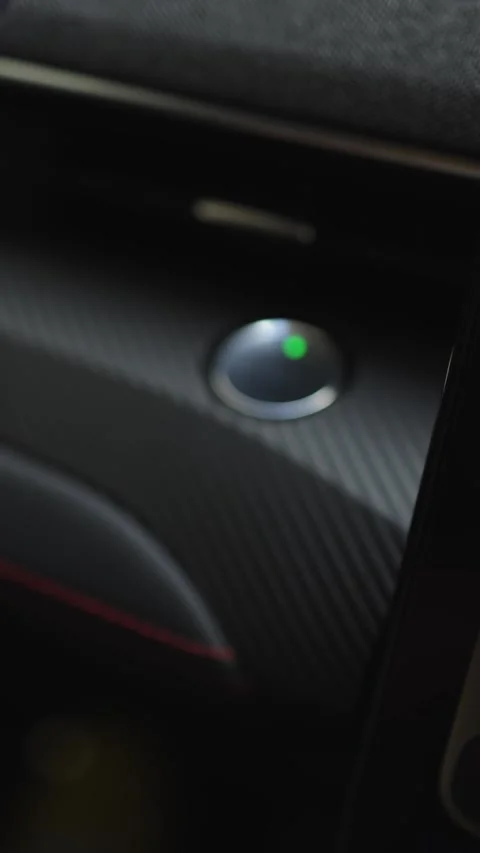 Hand pressing the power start button in a modern vehicle interior, showing a Stock Footage 337386196