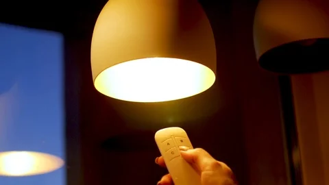 Hand pressing a remote control controlling an light Stock Footage 106953092