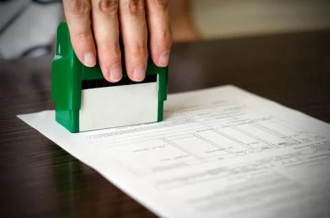 Hand pressing rubber stamp on document Stock Photos