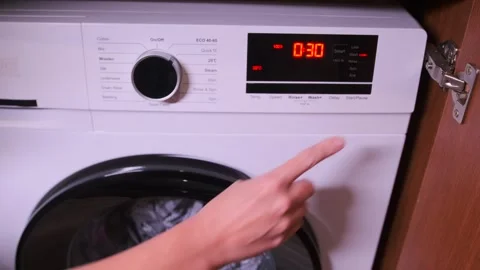 Hand pressing start button on front load washing machine control panel 動画素材 333649351
