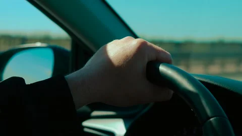 Hand pressing on steering wheel while unrecognizable man driving under clear sky Stock Footage 314268334