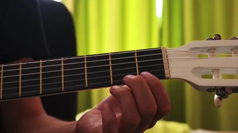 Hand pressing strings to form chords on a classical guitar fretboard Stock Footage 345521391