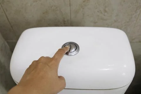 Hand is pressing the toilet flush button Photos