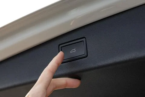 Hand pressing trunk release button inside a vehicle, showing interior detai.. Stockfoto's