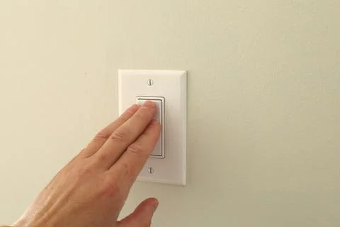 Hand pressing wall light switch 스톡 사진
