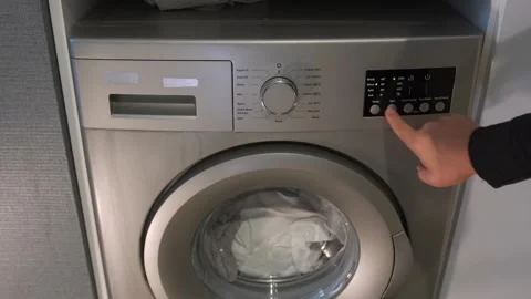 Hand pressing washing machine buttons close-up view, selecting wash program on 動画素材 333649266