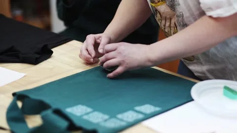 Hand-printed pattern on fabric. Women's hands put a seal on the shopping bag Stock Footage 170278270