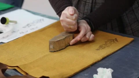 Hand-printed pattern on fabric. Women's hands put a seal on the shopping bag Stock Footage 236002998