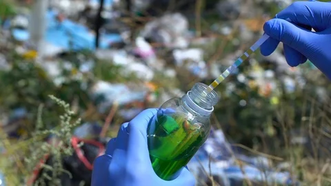 Hand in protective gloves measuring liquid acidity level on landfill, pollution Stock Footage 116210734