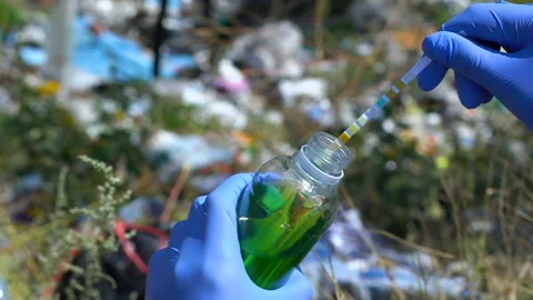 Hand in protective gloves measuring liquid acidity level on landfill, pollution Stock Footage 116212098