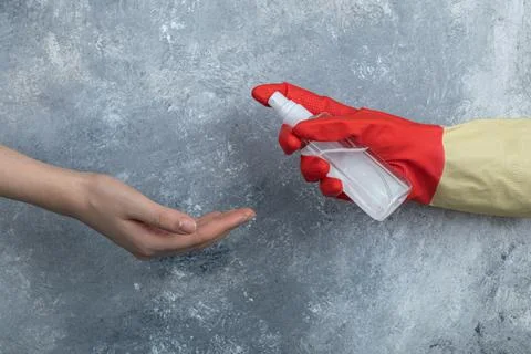 Hand in protective gloves spraying ethanol to woman Stock Photos