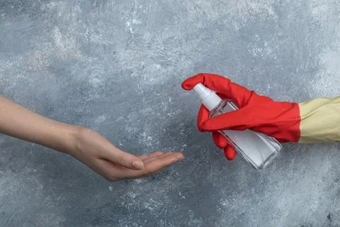 Hand in protective gloves spraying ethanol to woman Stock Photos