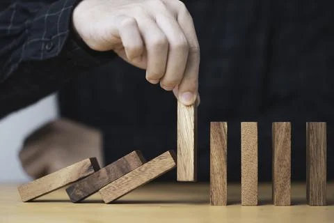 Hand pull out wooden block to prevent and stop falling domino ,It is a symb.. Stock Photos