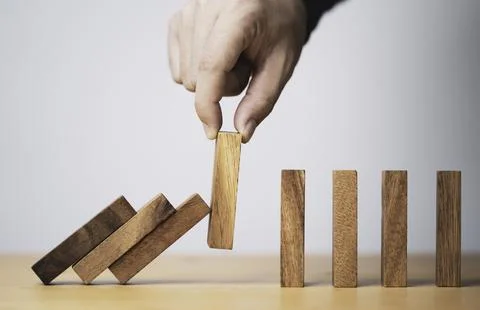 Hand pull out wooden block to prevent and stop falling domino ,It is a symb.. Stock Photos