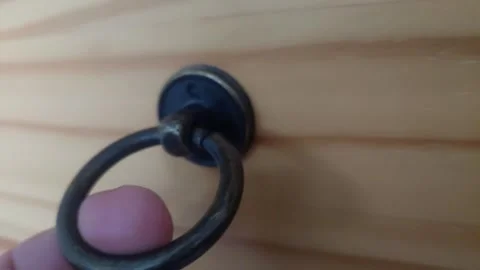 Hand pulling an antique metal ring handle on a wooden drawer Stock Footage 336461588