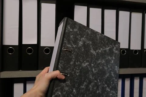 Hand Pulling Black Marble Office Binder from Shelf Stock Photos