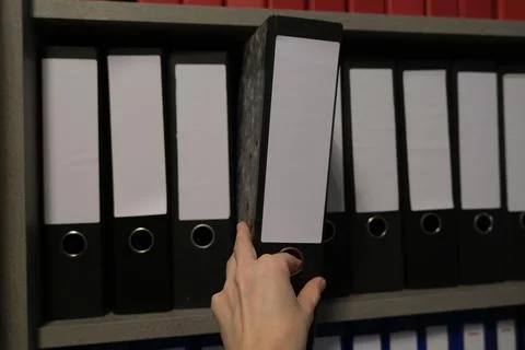 Hand Pulling Black Office Binder from Shelf Stock Photos