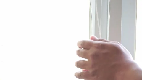 Hand pulling a blind cord to open a window covering. Vídeos de archivo 339122000