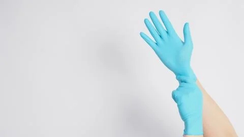 Hand is pulling blue latex gloves on white background. Stock Photos