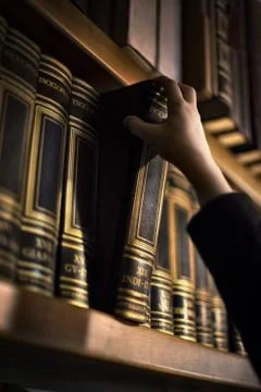 Hand pulling book from bookshelf 스톡 사진