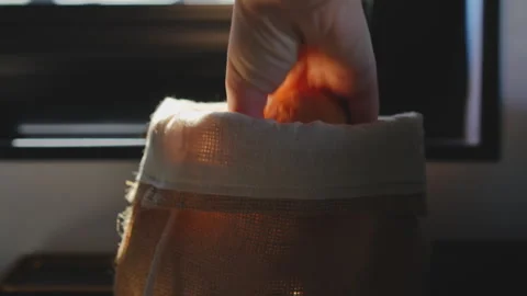 Hand pulling bread from burlap bag in slow motion backlight 库存影片 335459206