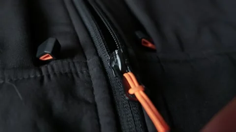 Hand Pulling Bright Orange Zipper String on Black Outdoor Jacket Video stock 338093783