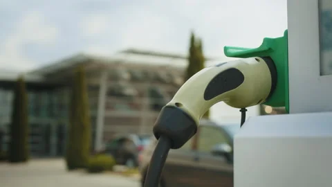 Hand pulling in cable from EV car charger or electric vehicle station. Cable Stock Footage 235229345
