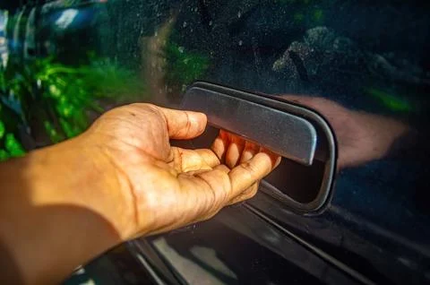 Hand pulling car door handle on dark surface with bright light and clear re.. Photos