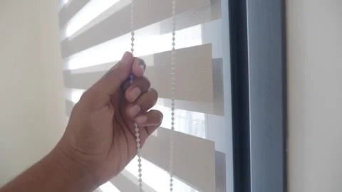 Hand pulling cord on dual layer zebra blinds for window light control motion. Stock Footage 332745427