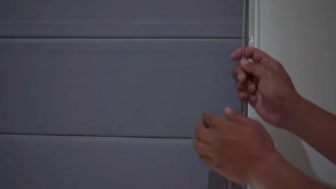 Hand pulling a curtain cord to open a window covering. Stock Footage 338428936