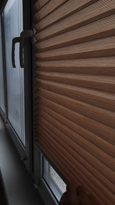 Hand Pulling Down Pleated Window Blind on a Rainy Day Stock Footage 325223508