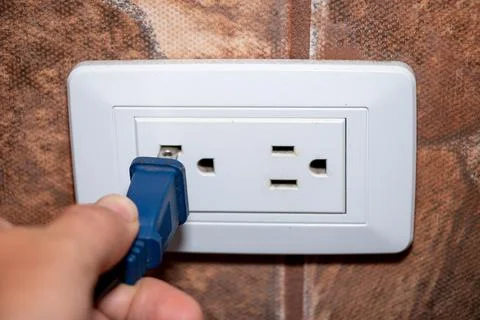 Hand pulling electrical plug from household power outlet isolated Stock Photos