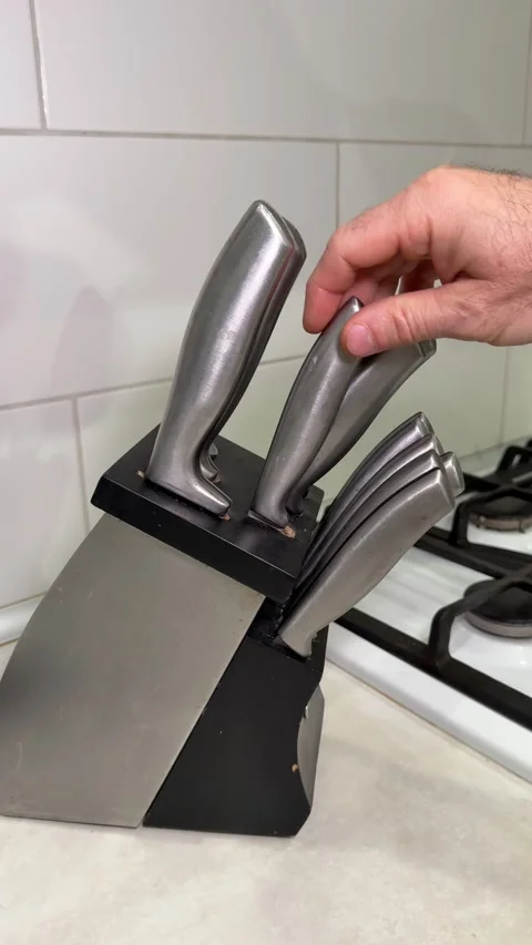 Hand pulling a kitchen knife from a wooden block. The shot highlights everyday Stock Footage 323510155