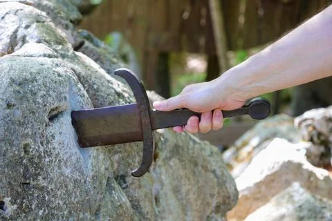 Hand pulling the legendary sword in the stone Excalibur representing streng.. Fotos Stock