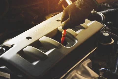 Hand is pulling oil dipstick to lube level checking Stock Photos