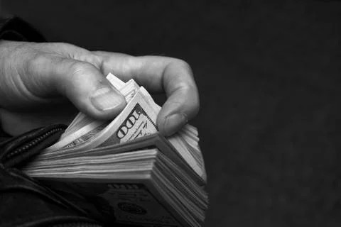 Hand pulling out a bundle of dollars Photos