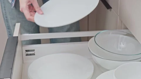 Hand pulling out kitchen drawer with neatly stacked plates and bowls Stock Footage 328232723