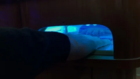 Hand pulling out of nail dryer blue light Stock Footage 98590233